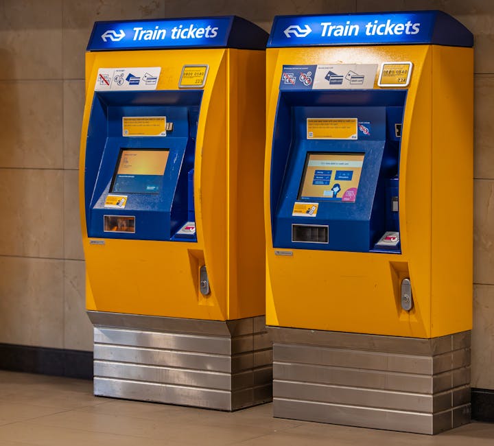 A night scene at Vauxhall Station showing a train stationary on the platform with its doors closed, illuminated overhead lighting, and a row of metal support beams with blue and green signs indicating accessible facilities. The platform surface consists of brick and tactile paving in yellow along the edge, with a black and silver waste bin positioned next to a support column. The background reveals a glimpse of the train track extending into the distance, and the station's roof structure visible overhead. Lambeth Removals is providing support for home relocation and furniture transport services, with the image illustrating the logistical environment where loading and unloading processes are managed in close proximity to transport vehicles, relevant to moving services in the Lambeth area.